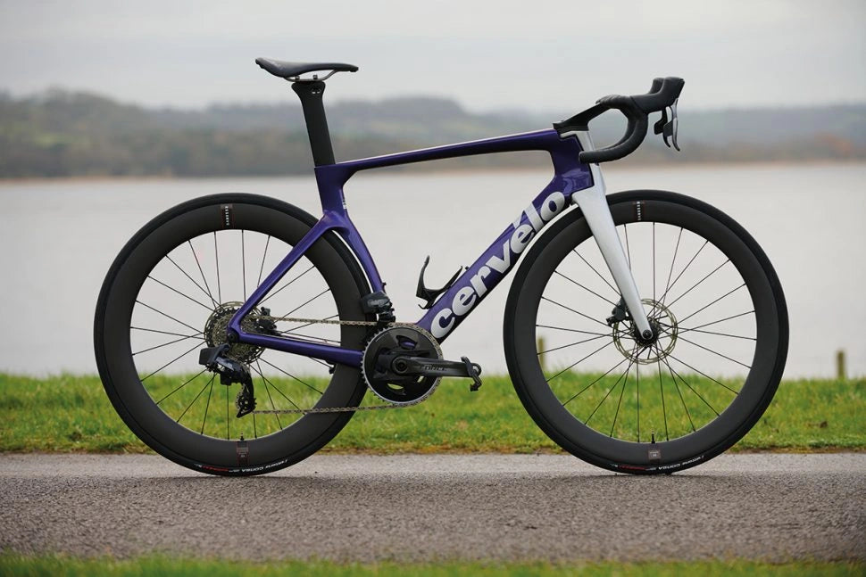 Aero racing bicycle with a purple and white frame, positioned in front of a lake.