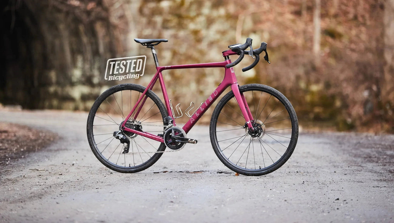 A maroon Allied road bike with 'Tested Bicycling' sign on a gravel path.