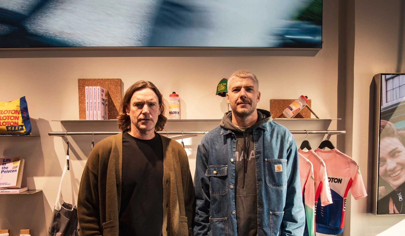 Two men standing in a cycling-themed store with various merchandise displayed around them.