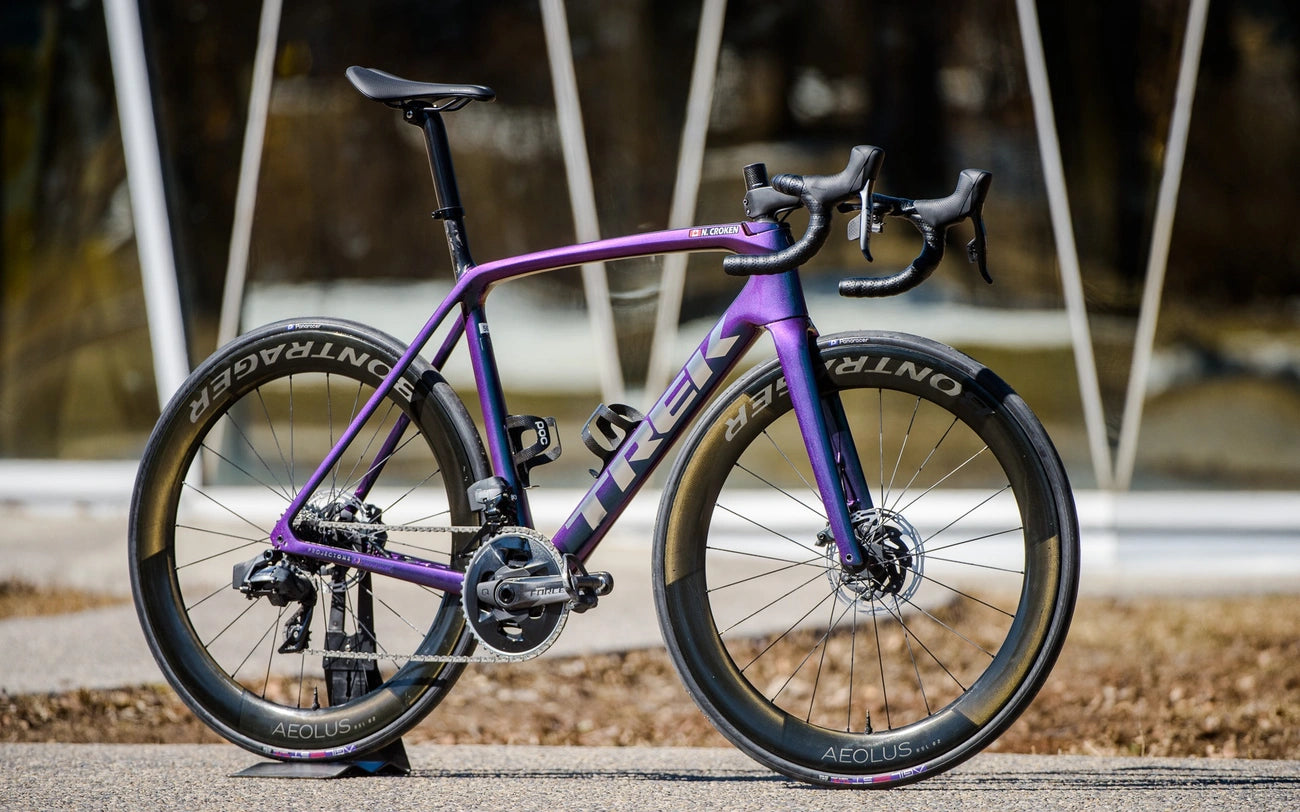 A sleek, purple road bike by Trek with aerodynamic design and high-performance wheels.